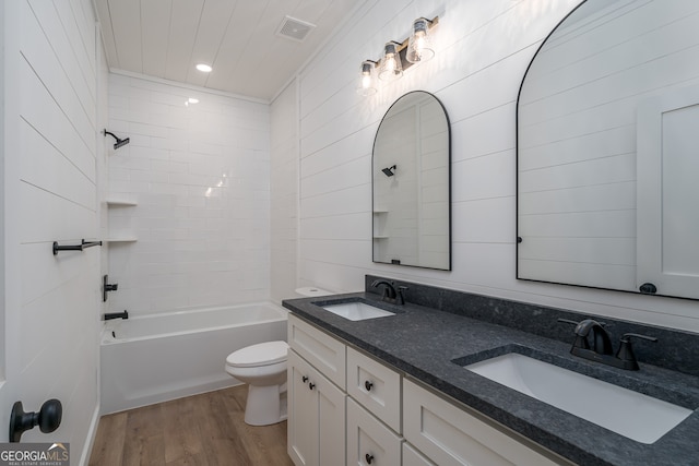 full bathroom with wood-type flooring, tiled shower / bath combo, vanity, and toilet