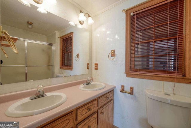 bathroom with vanity, ornamental molding, a shower with shower door, tile walls, and toilet