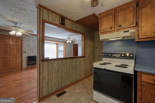 kitchen featuring wood walls, light hardwood / wood-style flooring, heating unit, white range with electric stovetop, and a textured ceiling