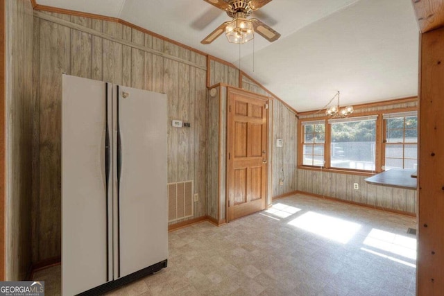 kitchen with lofted ceiling, wood walls, ceiling fan with notable chandelier, and white fridge