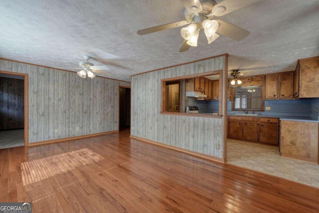 kitchen featuring a textured ceiling, ceiling fan, light hardwood / wood-style floors, ornamental molding, and electric range