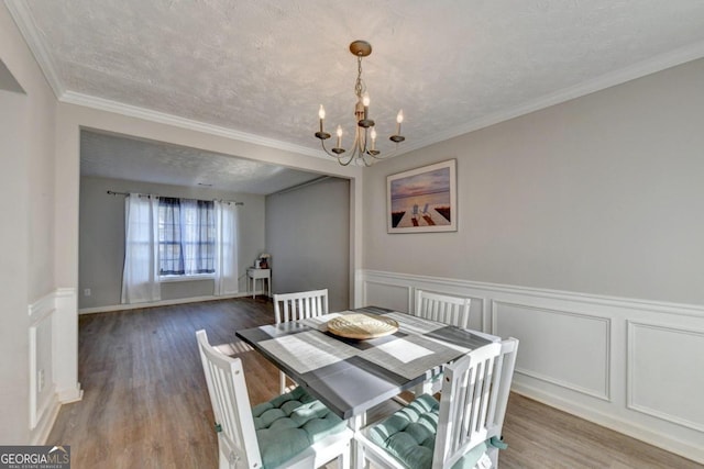 dining area with hardwood / wood-style flooring, crown molding, and a textured ceiling