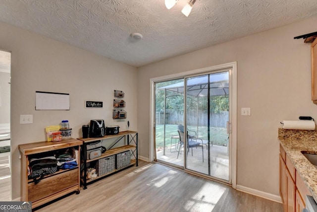 doorway featuring a textured ceiling and light hardwood / wood-style flooring