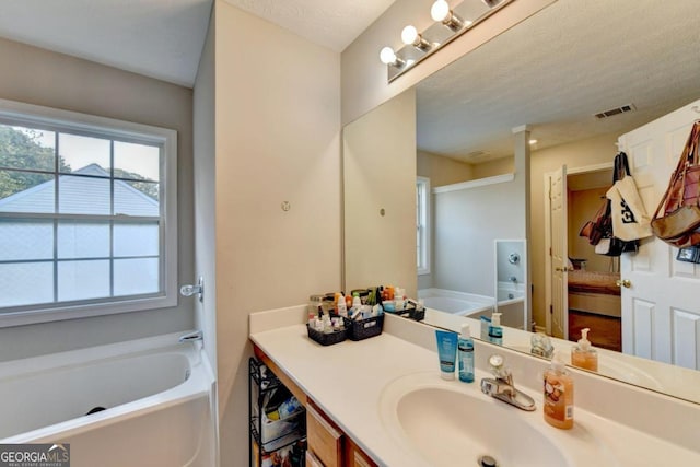 bathroom with a washtub, vanity, and a textured ceiling