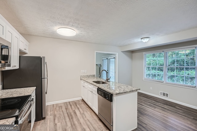 kitchen with light hardwood / wood-style flooring, white cabinets, appliances with stainless steel finishes, and sink