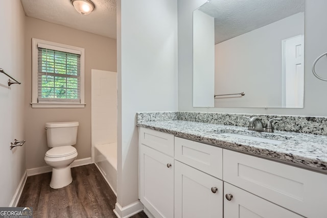 bathroom with a textured ceiling, hardwood / wood-style flooring, vanity, and toilet