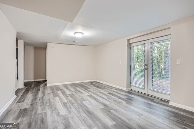 unfurnished room with french doors and light hardwood / wood-style flooring