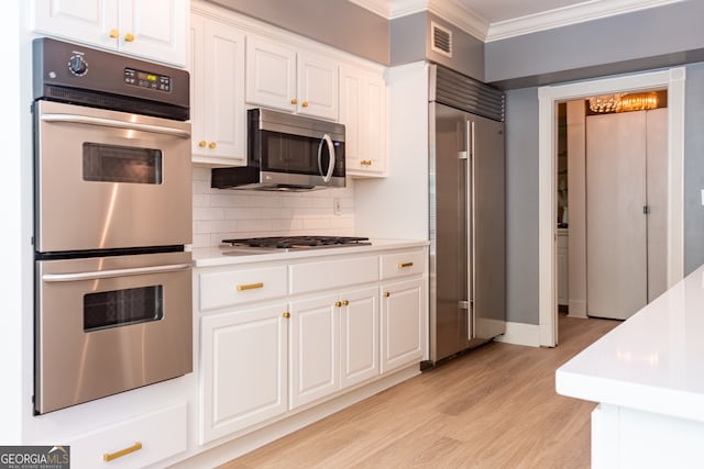 kitchen with stainless steel appliances, crown molding, white cabinets, and light wood-type flooring