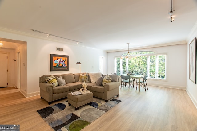 living room featuring ornamental molding, light wood-type flooring, a notable chandelier, and rail lighting