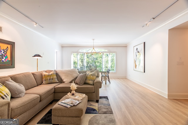 living room with ornamental molding, a chandelier, light hardwood / wood-style floors, and rail lighting