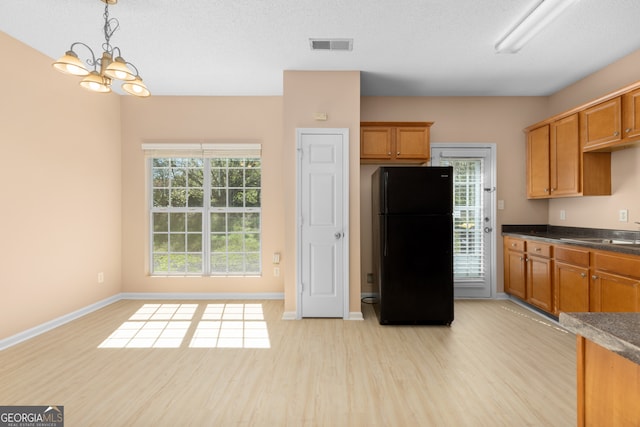 kitchen with pendant lighting, sink, light hardwood / wood-style flooring, a chandelier, and black refrigerator