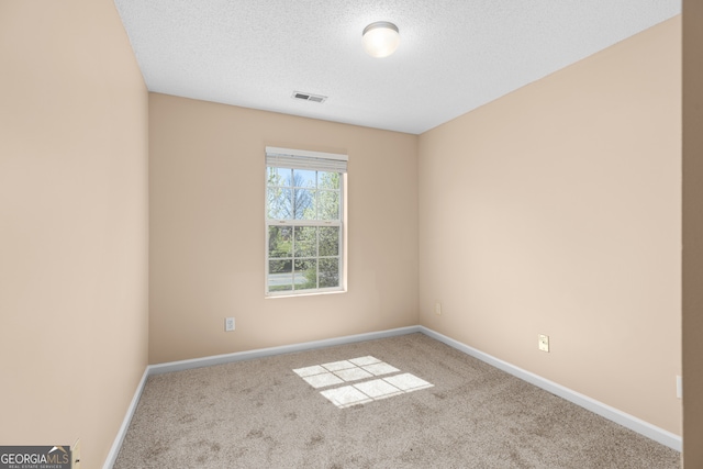 empty room featuring a textured ceiling and carpet