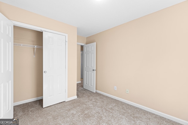 unfurnished bedroom featuring light carpet and a closet