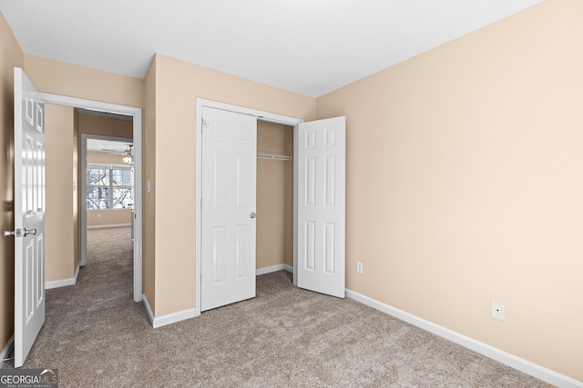 unfurnished bedroom with light colored carpet and a closet