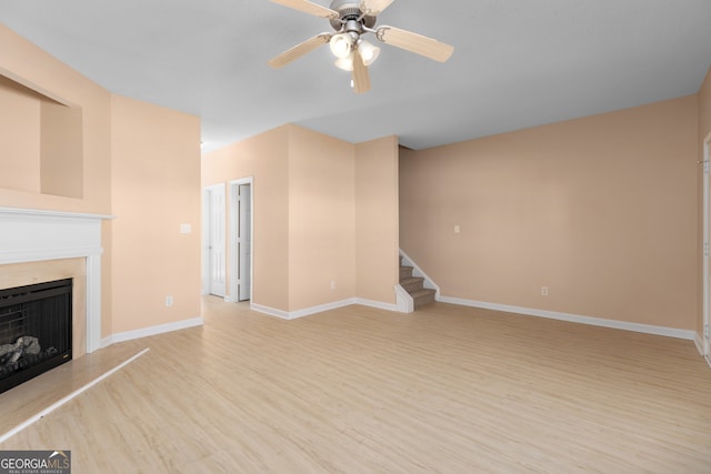 unfurnished living room with ceiling fan, light wood-type flooring, and a high end fireplace