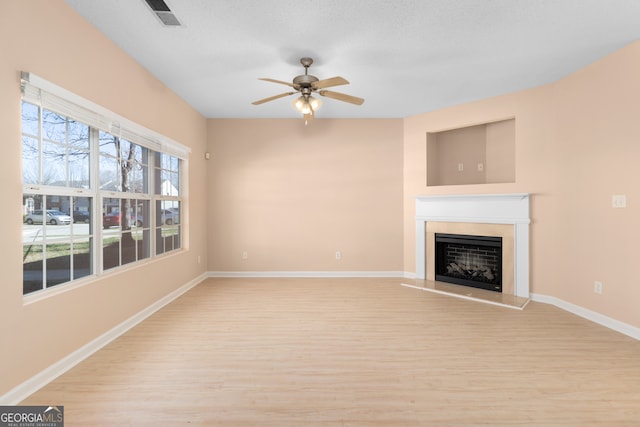 unfurnished living room with a textured ceiling, light wood-type flooring, and ceiling fan