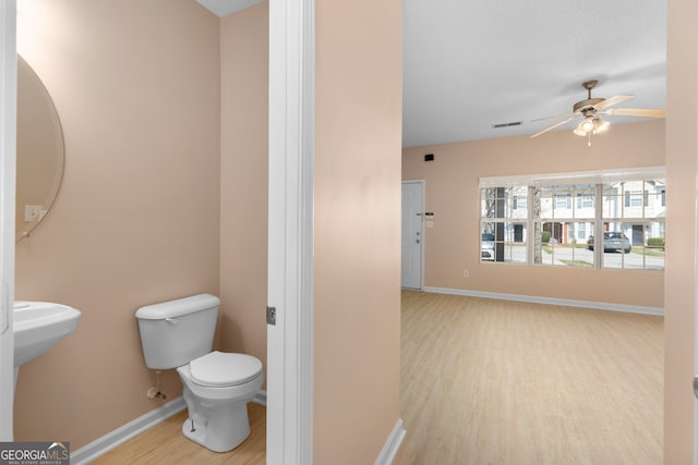 bathroom with wood-type flooring, ceiling fan, and toilet