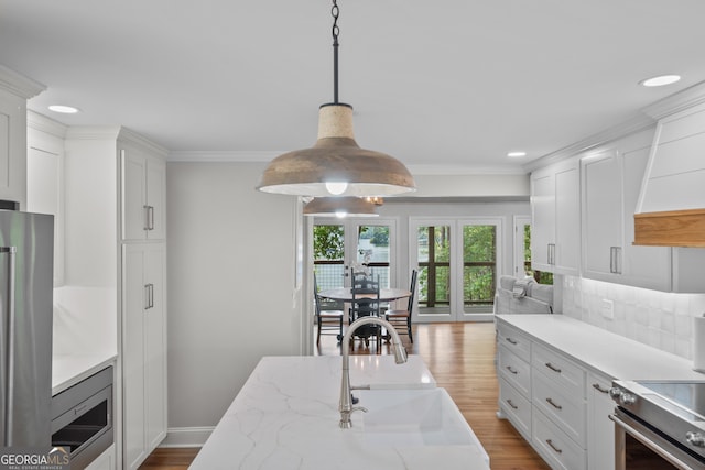 kitchen with white cabinetry, sink, stainless steel appliances, and light hardwood / wood-style flooring