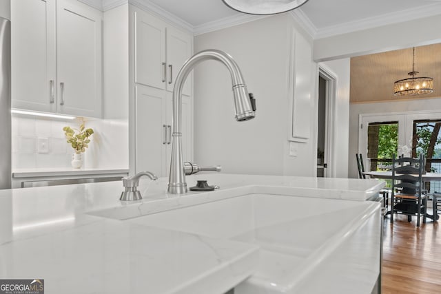 details with crown molding, a chandelier, sink, and wood-type flooring