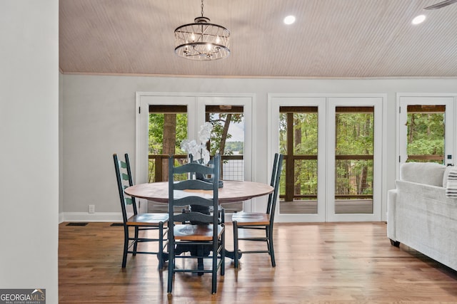 dining area with wood-type flooring, french doors, a notable chandelier, and a healthy amount of sunlight