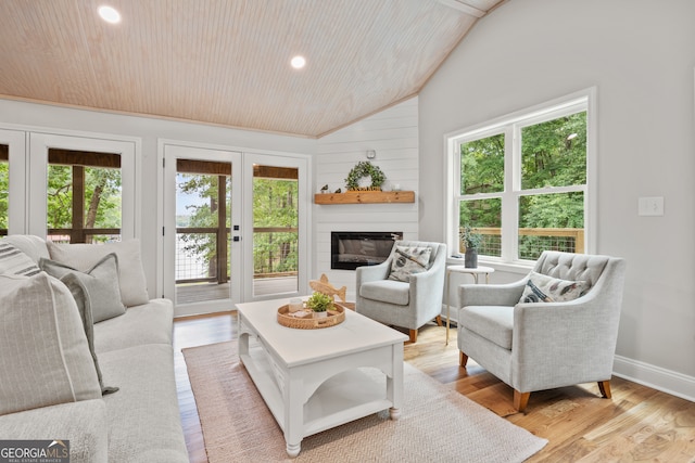 living room featuring wood walls, french doors, vaulted ceiling, wooden ceiling, and light hardwood / wood-style floors