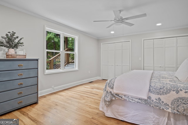 bedroom featuring ornamental molding, light wood-type flooring, ceiling fan, and two closets