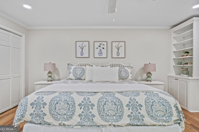 bedroom with a closet, crown molding, light wood-type flooring, and ceiling fan