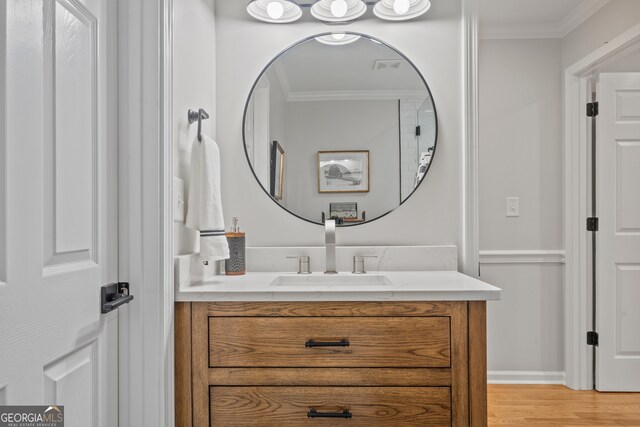 bathroom featuring hardwood / wood-style flooring, crown molding, and vanity