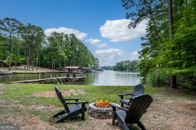 view of yard featuring an outdoor fire pit, a boat dock, and a water view