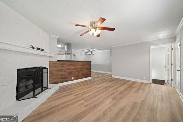 living room with ornamental molding, a fireplace, light wood-type flooring, and ceiling fan