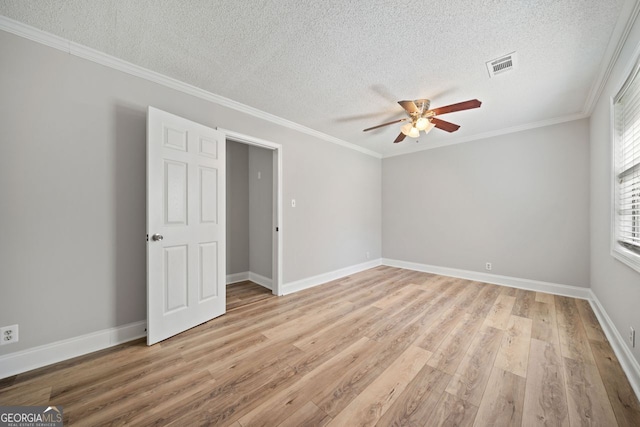 unfurnished room with ornamental molding, light hardwood / wood-style flooring, a textured ceiling, and ceiling fan