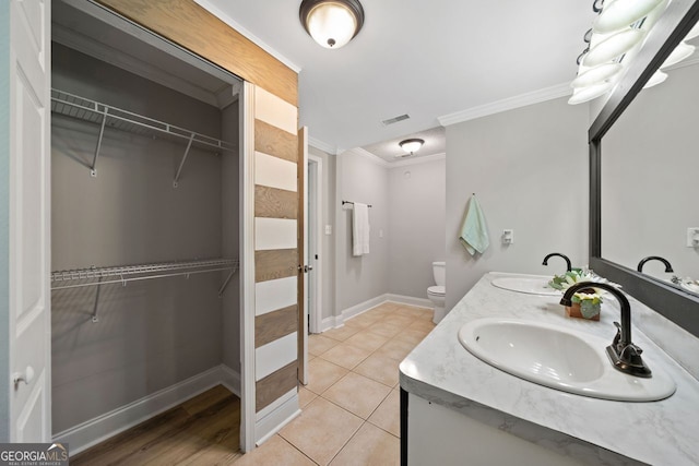 bathroom with vanity, toilet, crown molding, and tile patterned floors