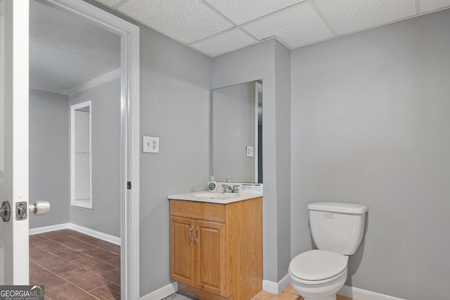 bathroom featuring vanity, toilet, a drop ceiling, and tile patterned flooring