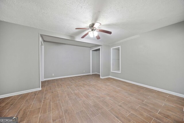 empty room featuring light hardwood / wood-style floors, a textured ceiling, and ceiling fan