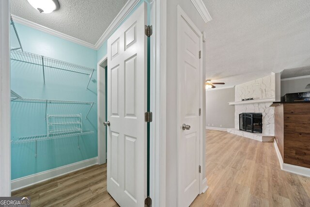 hallway featuring ornamental molding, a textured ceiling, and light wood-type flooring