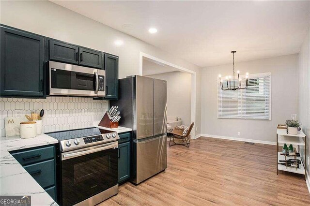 kitchen featuring light hardwood / wood-style floors, a chandelier, light stone counters, stainless steel appliances, and hanging light fixtures