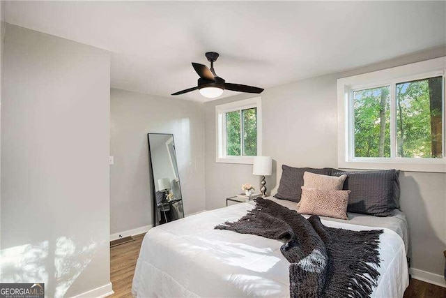 bedroom featuring multiple windows, baseboards, and wood finished floors