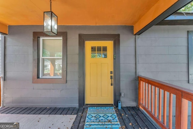 doorway to property featuring a porch and concrete block siding