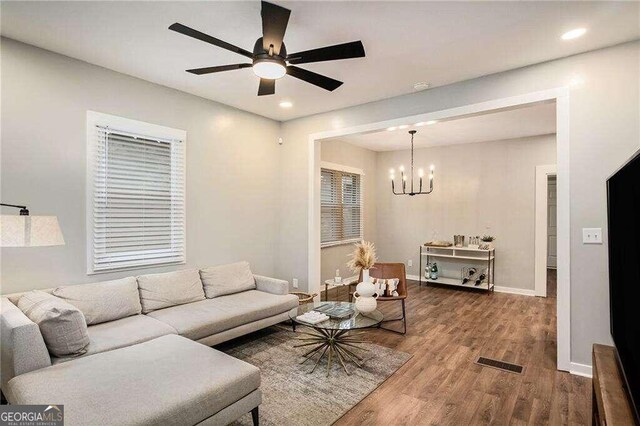 living room featuring ceiling fan with notable chandelier and hardwood / wood-style flooring