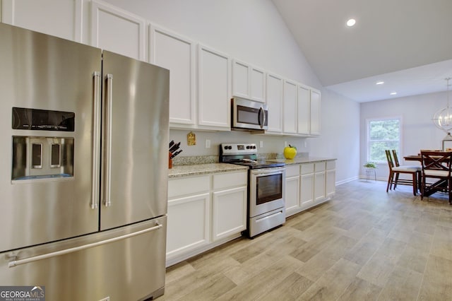 kitchen with light hardwood / wood-style floors, light stone counters, lofted ceiling, white cabinets, and appliances with stainless steel finishes