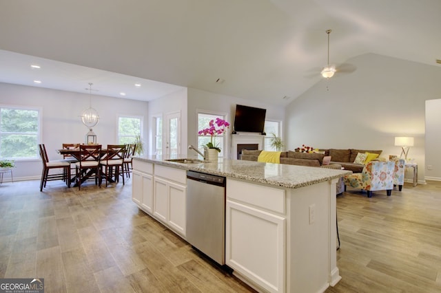 kitchen with light hardwood / wood-style floors, a center island with sink, dishwasher, white cabinets, and lofted ceiling