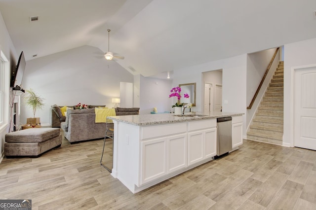 kitchen with white cabinets, vaulted ceiling, dishwasher, light stone countertops, and light hardwood / wood-style floors