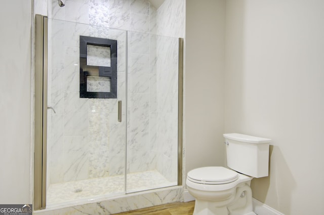 bathroom featuring wood-type flooring, a shower with shower door, and toilet