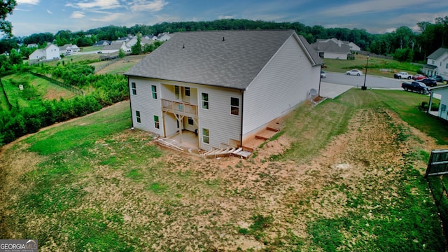 rear view of property featuring a balcony and a yard