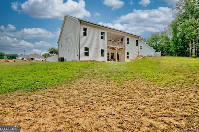 back of property with cooling unit, a balcony, and a lawn