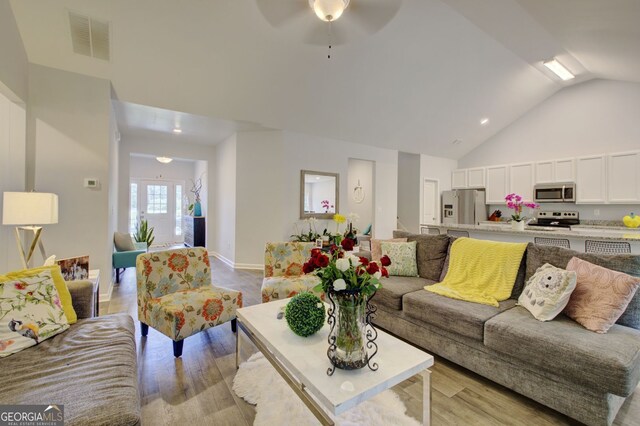 living room featuring lofted ceiling, light hardwood / wood-style floors, and ceiling fan