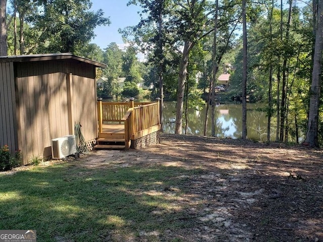 view of yard featuring ac unit and a deck with water view