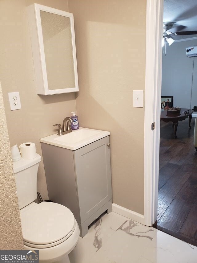 bathroom featuring ceiling fan, vanity, hardwood / wood-style floors, and toilet