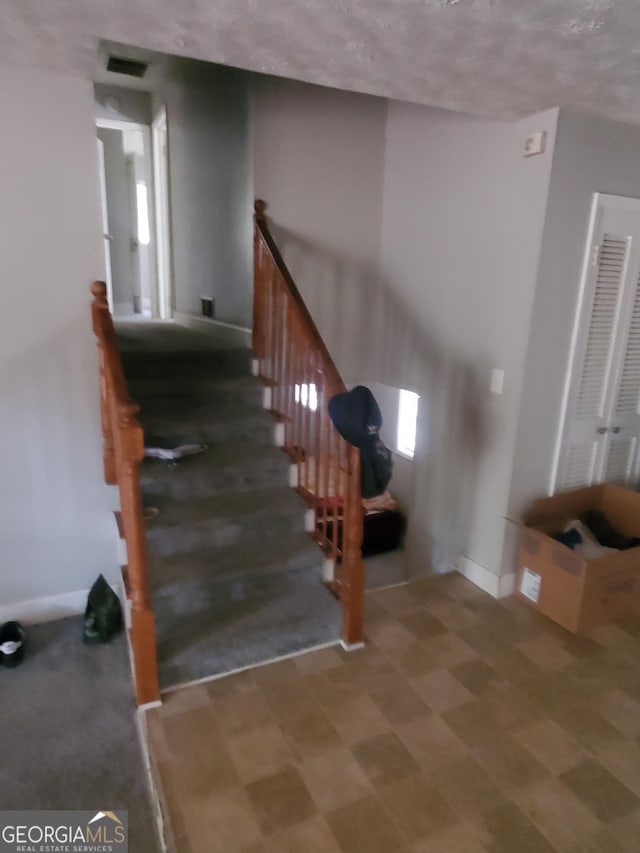 stairs featuring a textured ceiling