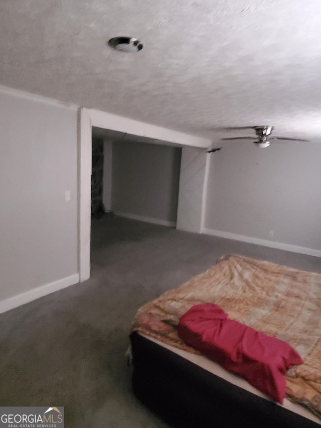 bedroom with a textured ceiling and dark colored carpet